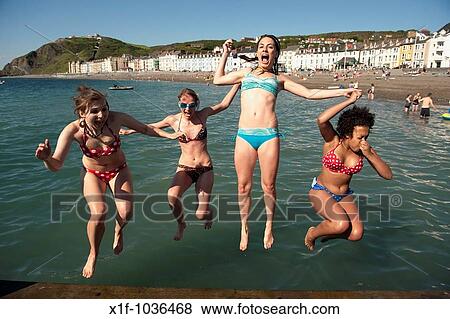 Four young women Aberystwyth university students jumping into the sea at the end of the academic year, June 2009, Wales UK View Large Photo Image Stock Photo - Four young women Aberystwyth university students jumping into the sea at the end of the academic year, June 2009, Wales UK. Fotosearch