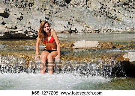 Fourteen year old girl in a bikini sits on a small waterfall in a creek View Large Photo Image Stock Photography - Fourteen year old girl in a bikini sits on a small waterfall in a creek. Fotosearch