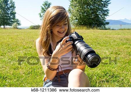 Fourteen year old girl sits on the grass in a Vancouver, BC park and reviews her photos on her digital camera. View Large Photo Image Stock Photograph - Fourteen year old girl sits on the grass in a Vancouver, BC park and reviews her photos on her digital camera.. Fotosearch