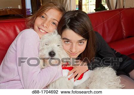 Stock Image - France, Alpes Maritimes, Mandelieu, Two girls with a Coton de Tulear.. Fotosearch