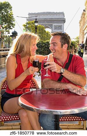 Stock Photo - France Attractive Tourist couple at caf? on Famous Champs Elysees and Arc de Triomphe in Paris France. Fotosearch