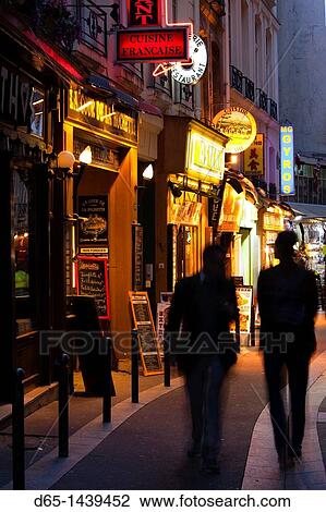 Stock Image - France, Paris, Left Bank, pedestrians on rue de Huchette, dusk. Fotosearch