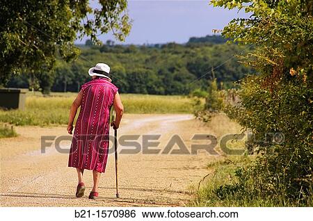 Stock Photograph - France-Poitou Charente- Vienne- old lady walking with a stock.. Fotosearch