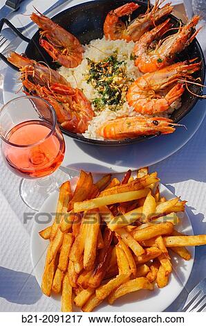 Stock Photo - France. Wine and Food: "Persillade de Gambas" (Big shrimps with garlic and persley sauce), "Frites" (french fries) and ros? wine.. Fotosearch