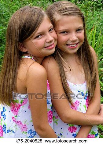 Stock Photo - fraternal twin sisters hugging. Fotosearch