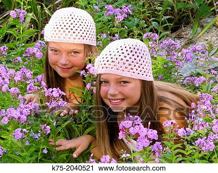 Stock Image - Fraternal twins in garden of flowers. Fotosearch
