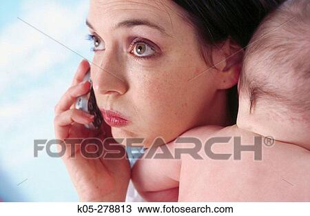 Frazzied mother on mobile phone holding infant View Large Photo Image Stock Image - Frazzied mother on mobile phone holding infant. Fotosearch
