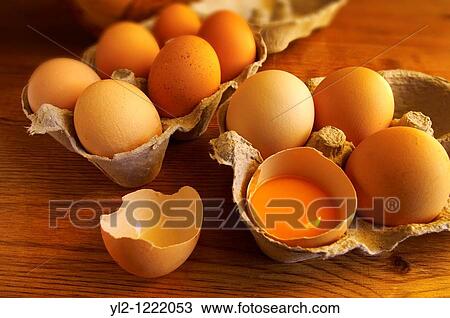Stock Image - Free range eggs, one cracked with a yoke, in a coutry kitchen setting. Fotosearch