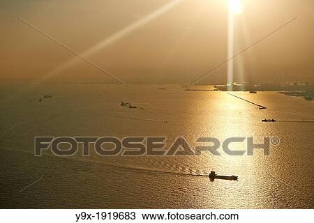 Freight ships sail in the ocean on a bright orange warm day View Large Photo Image Stock Image - Freight ships sail in the ocean on a bright orange warm day. Fotosearch