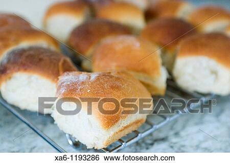 Stock Photograph - Freshly baked bread rolls cooling on a rack. Fotosearch