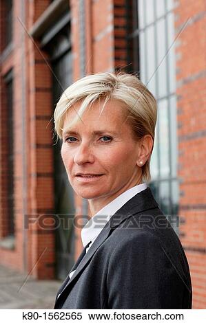 Friendly looking, blond haired executive woman with office building made of red bricks and windows in the background, Hamburg, Germany, Europe View Large Photo Image Stock Photography - Friendly looking, blond haired executive woman with office building made of red bricks and windows in the background, Hamburg, Germany, Europe. Fotosearch