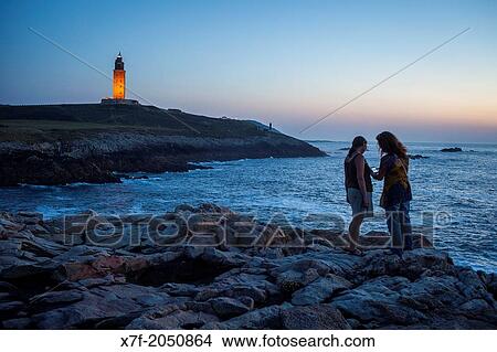 Friends in Punta Herminia gardens, in background Tower of Hercules, Roman lighthouse, Corua city, Galicia, Spain. View Large Photo Image Picture - Friends in Punta Herminia gardens, in background Tower of Hercules, Roman lighthouse, Corua city, Galicia, Spain.. Fotosearch