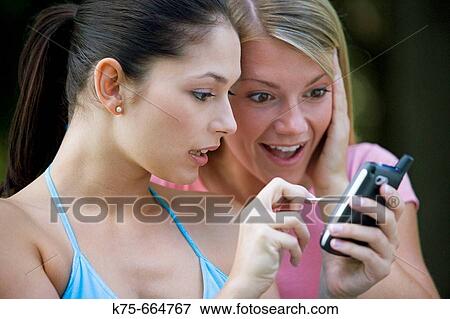 Friends sharing use of wireless handheld View Large Photo Image Stock Photo - Friends sharing use of wireless handheld. Fotosearch