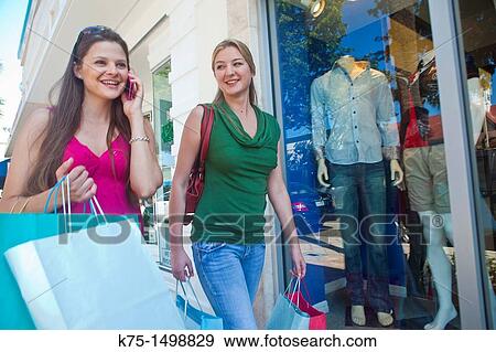 Friends shopping while one is talking on cell phone View Large Photo Image Stock Photo - Friends shopping while one is talking on cell phone. Fotosearch