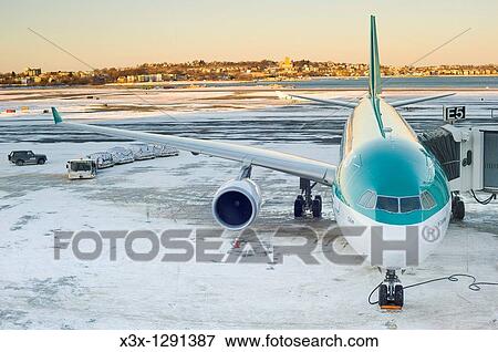 Stock Photo - Front high angle view of passenger airplane parked on runway with snow during loading unloading. Fotosearch