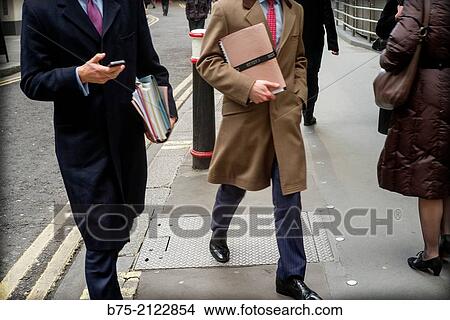 Picture - front view of two unrecognizable executive with folders documents walking down the street in London, England, UK, Europe. Fotosearch