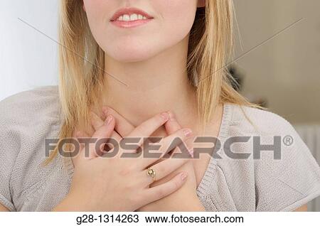 Front view of young woman holding her lower throat with her 2 hands dressed in grey detail, for breathing problems, asthma, or thyroid gland detail View Large Photo Image Stock Image - Front view of young woman holding her lower throat with her 2 hands dressed in grey detail, for breathing problems, asthma, or thyroid gland detail. Fotosearch