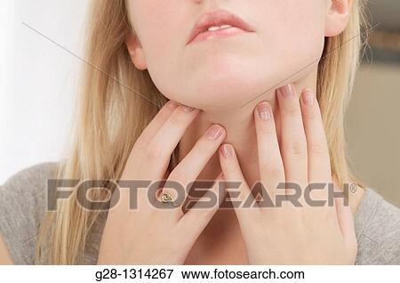 Front view of young woman holding her lower throat with her 2 hands dressed in grey detail, for breathing problems, asthma, or thyroid gland detail View Large Photo Image Stock Photo - Front view of young woman holding her lower throat with her 2 hands dressed in grey detail, for breathing problems, asthma, or thyroid gland detail. Fotosearch