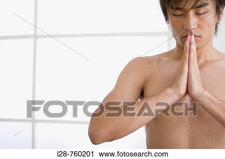 Stock Image - Front view portrait of young man performing yoga. Fotosearch