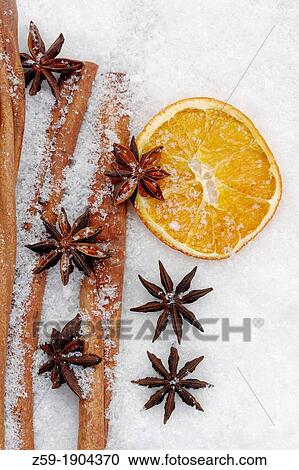Stock Image - fruits of star anise - Illicium verum - cinnamon sticks - Cinnamomum cassia - dried orange slices - potpourri on artificial snowflakes. Fotosearch