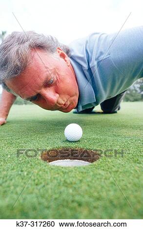 Frustrated man attempting to blow his golf ball into the hole View Large Photo Image Stock Image - Frustrated man attempting to blow his golf ball into the hole. Fotosearch