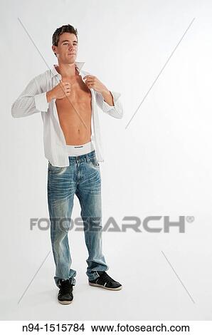 Picture - Full-body photograph of a teenage boy standing by getting a white shirt.. Fotosearch