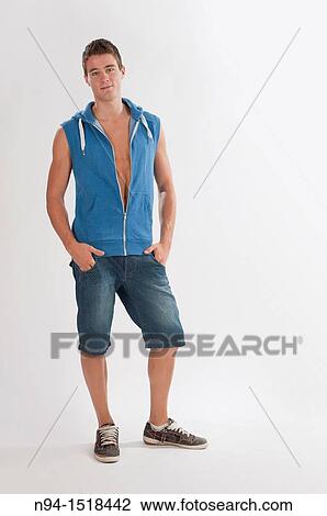 Stock Image - Full-body photograph of a teenage boy, with jeans and short blue sleeveless vest.. Fotosearch