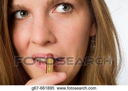 Full face of mid 20's woman applying make up to her lips View Large Photo Image Stock Photography - Full face of mid 20's woman applying make up to her lips. Fotosearch