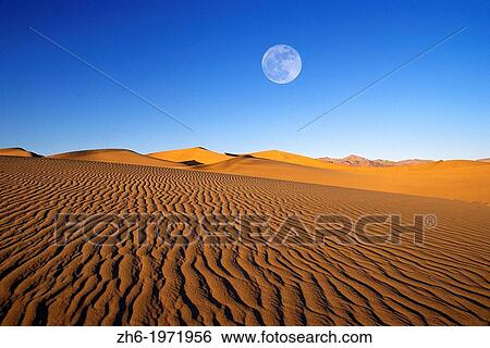 Stock Photograph - Full moon over evening light on dune patterns on the Mesquite Flat Sand Dunes, Death Valley National Park, California USA.. Fotosearch