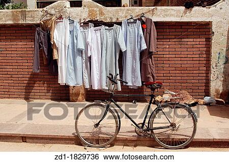 Galabayyas hanging on a clothes line on a street with a bike in Cairo, Egypt View Large Photo Image Stock Photograph - Galabayyas hanging on a clothes line on a street with a bike in Cairo, Egypt. Fotosearch