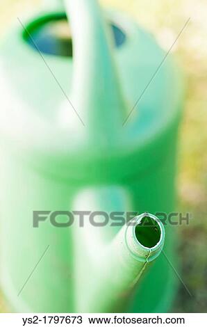 Stock Image - Gardening equipment, green plastic watering can in a garden at summertime. Fotosearch