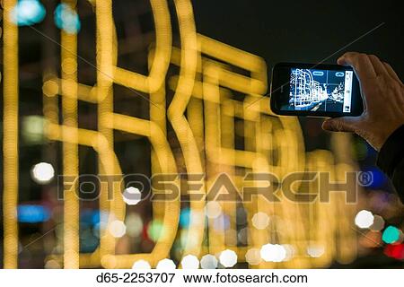 Stock Photo - Germany, Berlin, Charlottenburg, Kurfurstendam, Berlin sign being photographed with cell phone, dusk.. Fotosearch