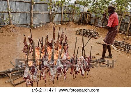 Stock Image - getting ready for a feast; barbecued meat in the Omo Valley, Ethiopia.. Fotosearch