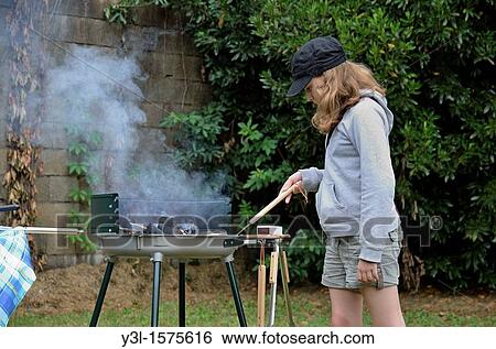 Stock Photograph - Girl 11 at barbecue in the garden, France. Fotosearch