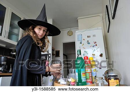 Stock Photography - Girl 11 disguised as witch on Halloween day, preparing special beverages in kitchen for her party. Fotosearch