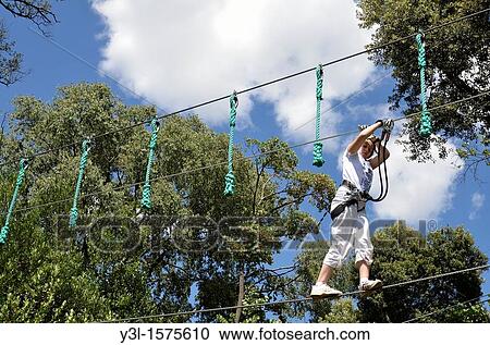 Stock Image - Girl 11 walking on suspended cables in adventure park, Marseille, France. Fotosearch