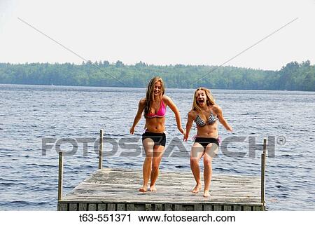 Stock Image - girl 13 girl 18 yrs about to jump into lake from dock. Fotosearch
