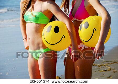 girl 13, girl 18 yrs standing on beach holding smile beach balls View Large Photo Image Picture - girl 13, girl 18 yrs standing on beach holding smile beach balls. Fotosearch