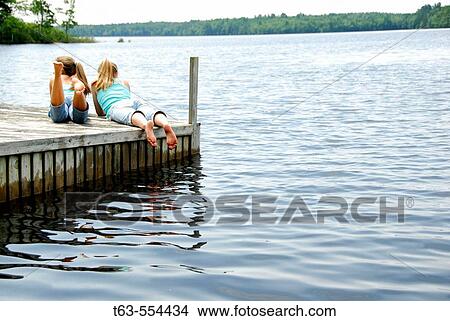 girl 13 with girl 18 together on dock looking out at lake View Large Photo Image Picture - girl 13 with girl 18 together on dock looking out at lake. Fotosearch