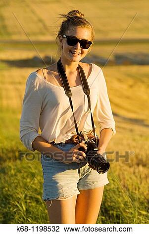 Stock Image - girl, 14, with camera, in a field in southern Alberta, Canada. Fotosearch