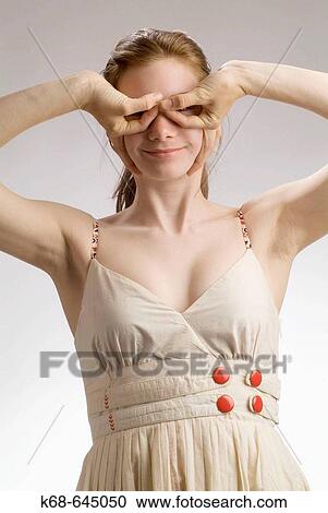 Stock Image - girl, 16, in a studio portrait, making a gesture of wearing glasses. Fotosearch