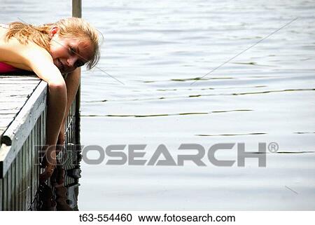 girl 18 laying on dock with hands in lake View Large Photo Image Stock Image - girl 18 laying on dock with hands in lake. Fotosearch