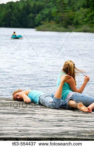 Stock Photo - girl 18 looking at camera, girl 13 looking at mother out in the lake. Fotosearch