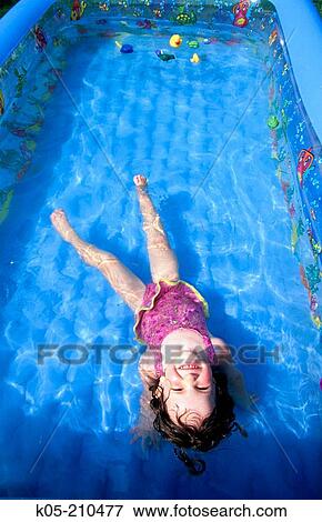 Girl (3yr) floating in an inflatable pool View Large Photo Image Stock Photo - Girl (3yr) floating in an inflatable pool. Fotosearch