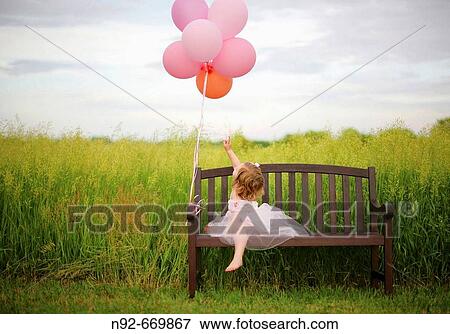 Girl, age 3 looking at balloons. In Illinois at farm. Hay feild. View Large Photo Image Stock Photo - Girl, age 3 looking at balloons. In Illinois at farm. Hay feild.. Fotosearch