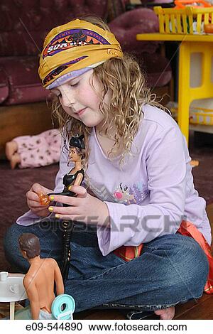 Girl, age 8 or 9, wearing Survivor buff on head, sitting on floor playing with Barbies, toys and couch in background View Large Photo Image Stock Image - Girl, age 8 or 9, wearing Survivor buff on head, sitting on floor playing with Barbies, toys and couch in background. Fotosearch