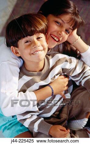 Stock Photography - Girl and young boy hugging and smiling at home. Fotosearch