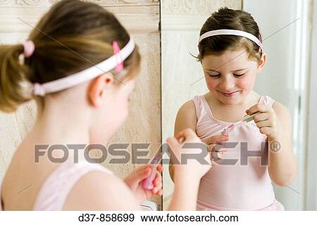 Girl applying make up in front of the mirror View Large Photo Image Stock Photo - Girl applying make up in front of the mirror. Fotosearch