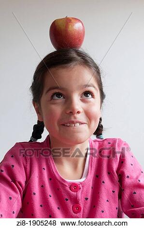 Girl balancing an apple on her head View Large Photo Image Stock Photo - Girl balancing an apple on her head. Fotosearch