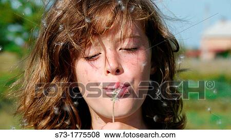 Girl blowing on a dandelion View Large Photo Image Stock Photo - Girl blowing on a dandelion. Fotosearch